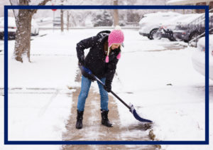 Woman in pink hat shoveling snow