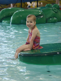 Photo of child sitting with their feet int the pool at the Indoor Aquatics Center